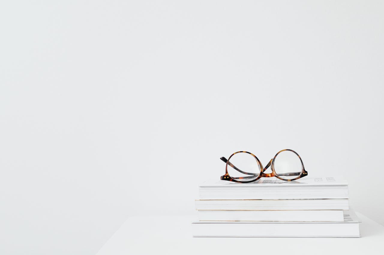 Eyeglasses on stacked books against a clean white background, perfect for educational themes.